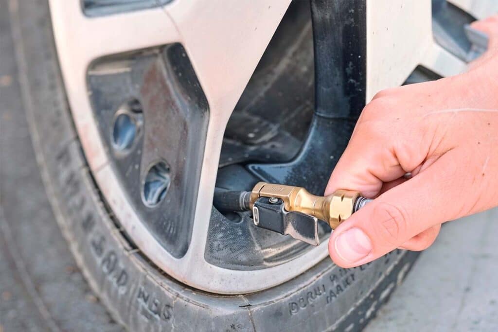 Foto de uma pessoa calibrando o pneu de um carro.