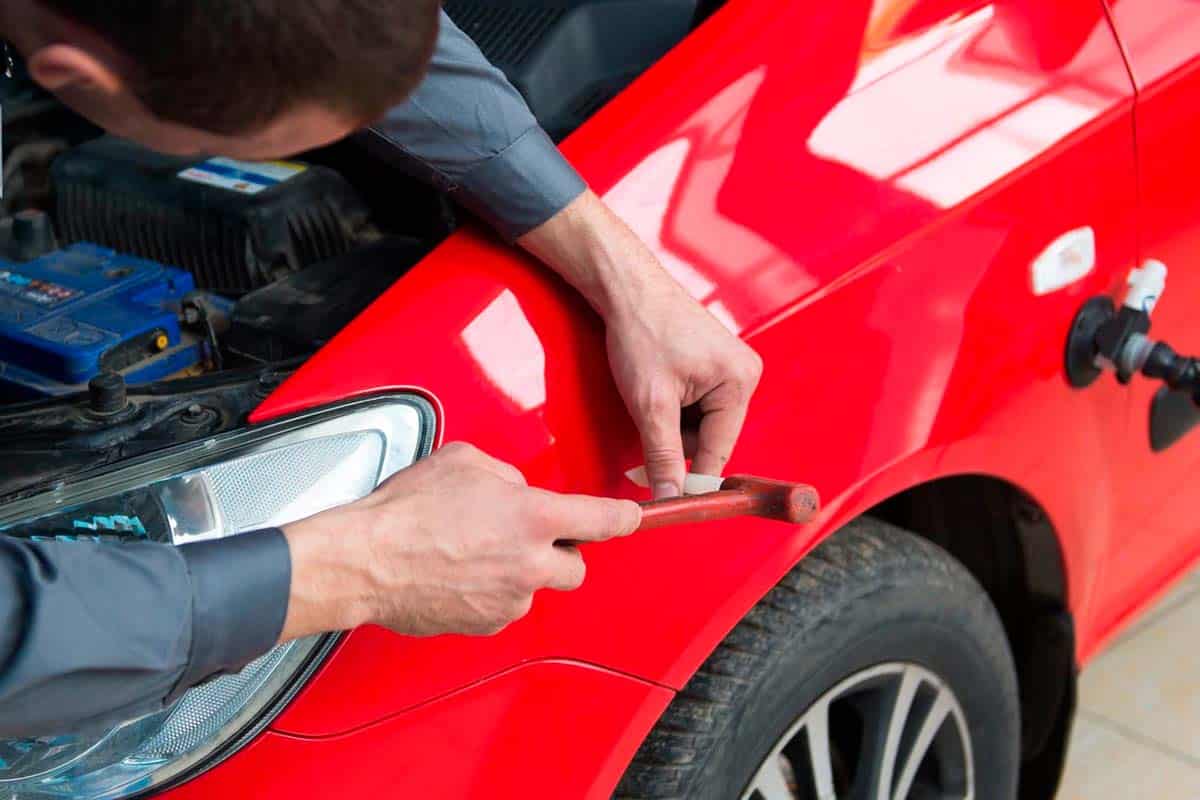 Foto de um técnico realizando o martelinho de ouro em um carro.