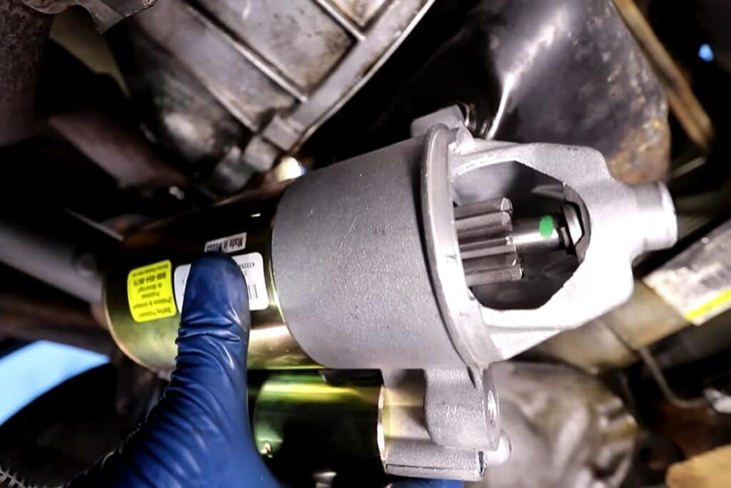 Foto de um mecânico segurando o motor de partida de um carro.