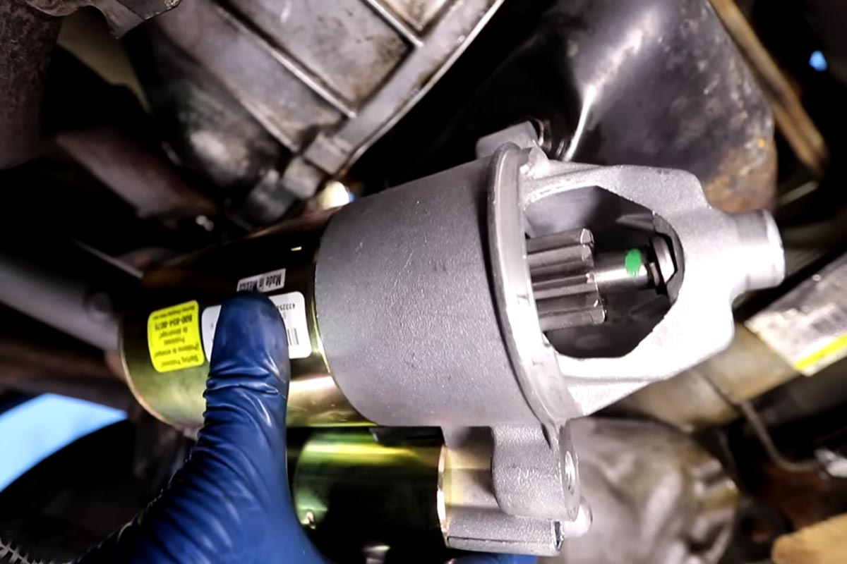 Foto de um mecânico segurando o motor de partida de um carro.