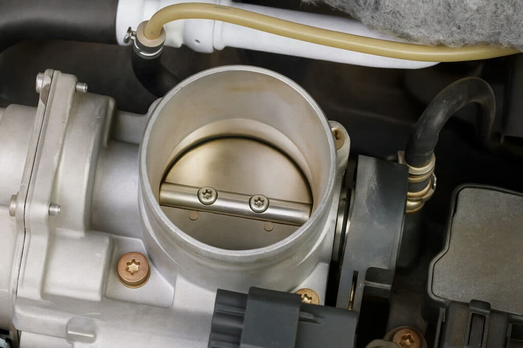 A imagem mostra um corpo de borboleta dentro do motor de um carro.