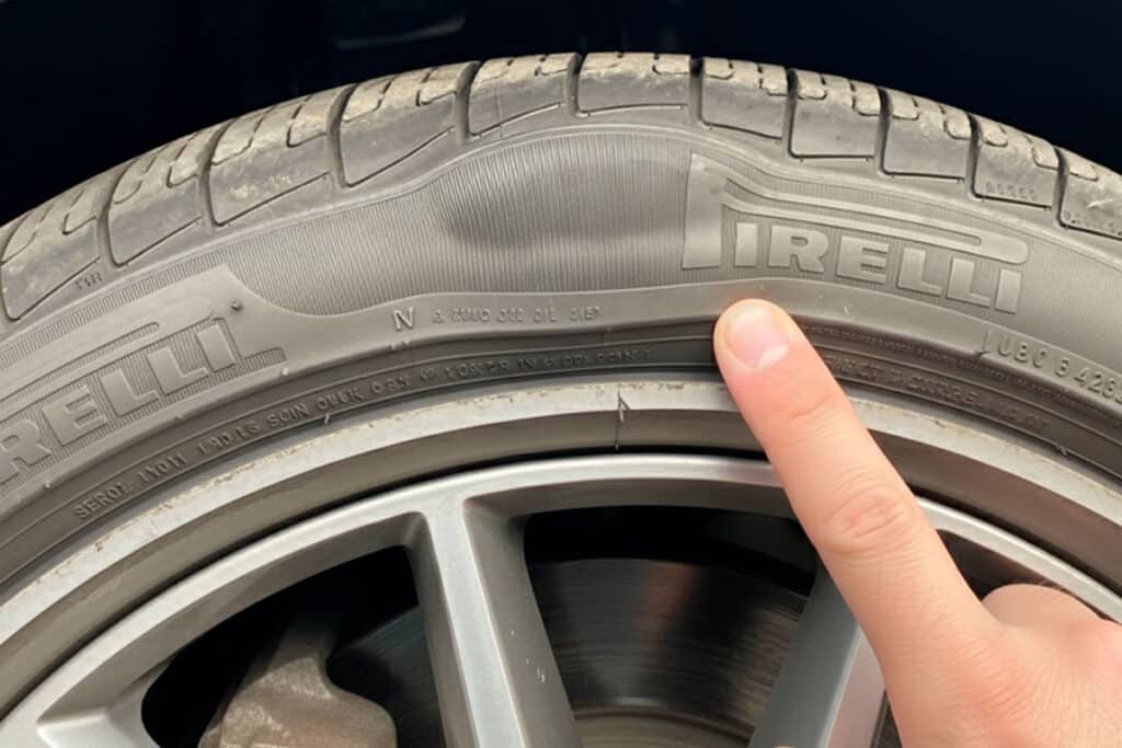 A imagem mostra um pneu Pirelli com uma bolha na lateral.
